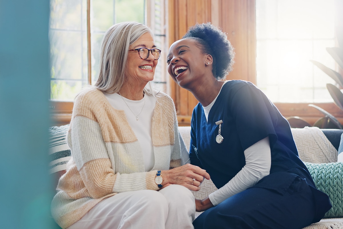 Senior patient, funny or happy caregiver talking for healthcare support at nursing home clinic. Smile, women laughing or nurse speaking of joke to a mature person or woman in a friendly conversation